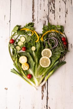 Overhead view of fresh green vegetables arranged as heart shape on white wooden table. unaltered, food, healthy eating, organic concept.