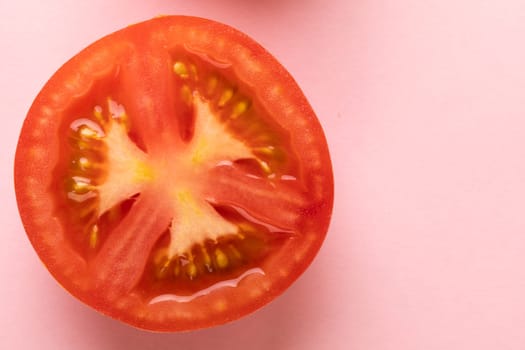 Overhead view of fresh red tomato halved cross section by copy space against pink background. unaltered, food, healthy eating, organic concept.