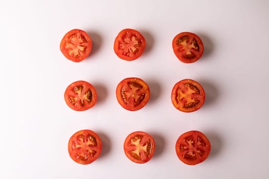 Overhead view of fresh tomato halves arranged in a row on white background. unaltered, food, healthy eating, organic concept.