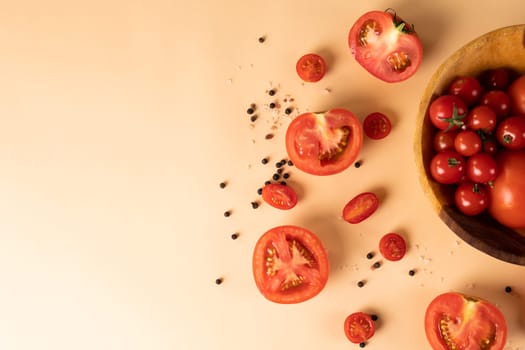 Overhead view of fresh red tomatoes with peppercorn by copy space on peach colored background. unaltered, food, healthy eating, organic concept.