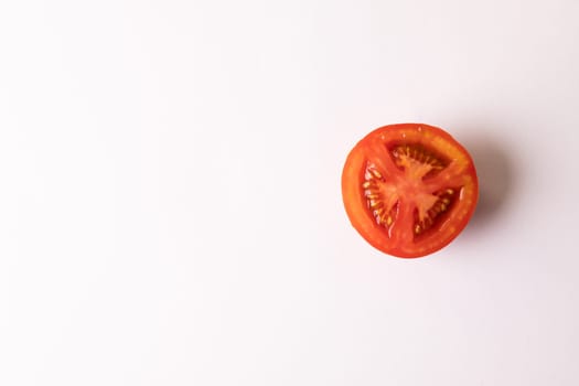 Directly above view of fresh red single tomato half by copy space on white background. unaltered, food, healthy eating, organic concept.