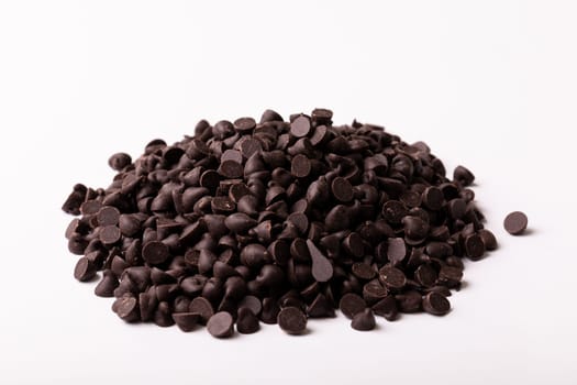 High angle view of fresh chocolate chips pile on white background. unaltered, sweet food and unhealthy eating concept.