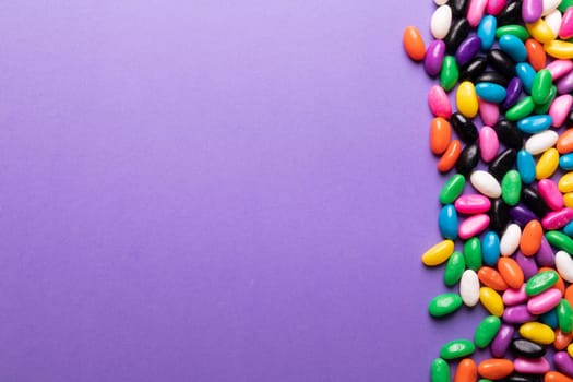 Directly above view of colorful sweet candies by copy space on purple background. unaltered, sweet food and unhealthy eating concept.