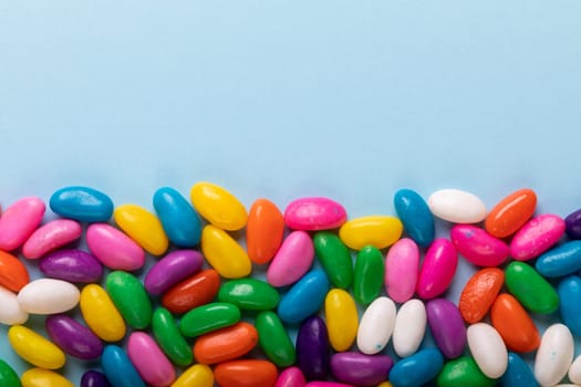 Overhead view of copy space and multi colored candies over blue background. unaltered, sweet food and unhealthy eating concept.