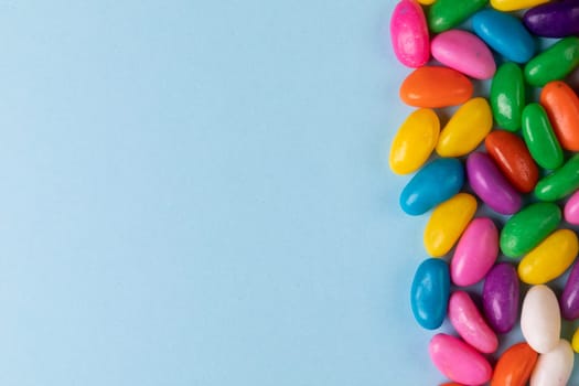 Overhead view of sweet multi colored candies on blue background with copy space. unaltered, sweet food and unhealthy eating concept.