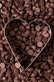 Full frame shot of fresh chocolate chips with heart shape pastry cutter. unaltered, sweet food and unhealthy eating concept.