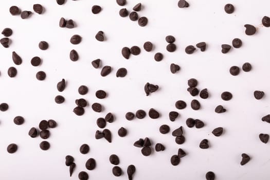 Full frame shot of fresh chocolate chips scattered over white background. unaltered, sweet food and unhealthy eating concept.