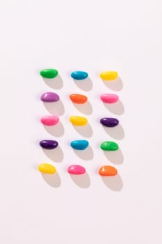 Overhead view of multi colored candies arranged in a row by copy space against white background. unaltered, sweet food and unhealthy eating concept.