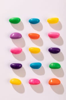 Overhead view of multi colored candies in a row over white background. unaltered, sweet food and unhealthy eating concept.