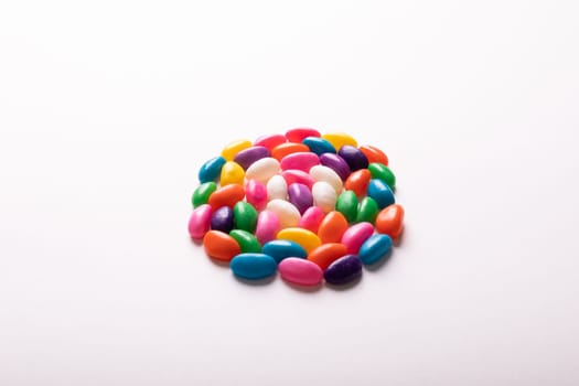 High angle view of multi colored candies arranged in circle by copy space against white background. unaltered, sweet food and unhealthy eating concept.