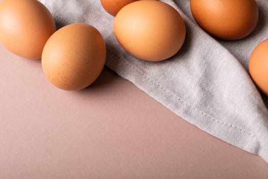 Close-up high angle view of fresh brown eggs and gray napkin over colored background with copy space. unaltered, food, healthy eating concept.