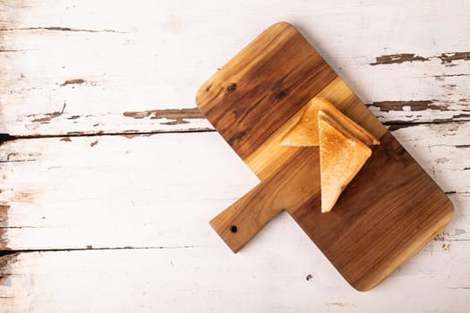 Overhead view of fresh fresh cheese sandwich on wooden serving board over white table. unaltered, food, unhealthy eating and snack concept.