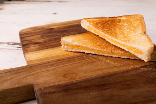 High angle view of fresh cheese sandwich on brown wooden serving board. unaltered, food, unhealthy eating and snack concept.