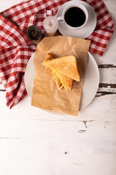 Directly above view of cheese sandwich by black coffee and bottles on checked napkin over table. unaltered, food, unhealthy eating and snack concept.