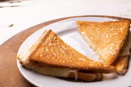 High angle view of fresh cheese sandwich served in plate on wooden serving board. unaltered, food, unhealthy eating and snack concept.