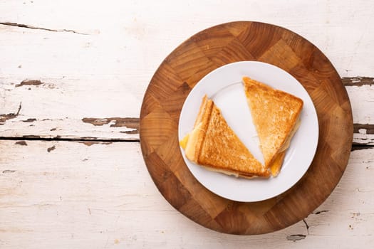 Directly above view of fresh cheese sandwich served in plate on wooden board over white table. unaltered, food, unhealthy eating and snack concept.