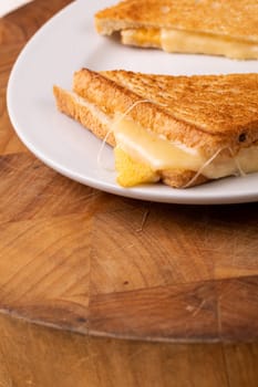 Close-up of fresh cheese toast sandwich served in plate on wooden board. unaltered, food, unhealthy eating and snack concept.