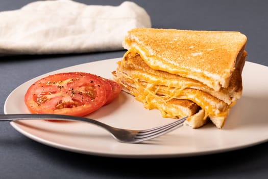 Close-up of fresh tomato slices with cheese toast sandwich and fork served in plate. unaltered, food, unhealthy eating and snack concept.