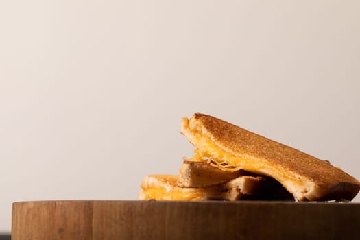 Close-up of cheese toast sandwich on wooden serving board against white background with copy space. unaltered, food, unhealthy eating and snack concept.