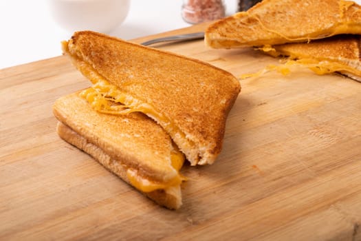 High angle view of fresh cheese toast sandwich served on wooden serving board. unaltered, food, unhealthy eating and snack concept.