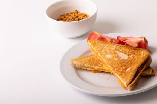 High angle view of fresh cheese sandwich served with tomato slices in plate on white background. unaltered, food, unhealthy eating and snack concept.