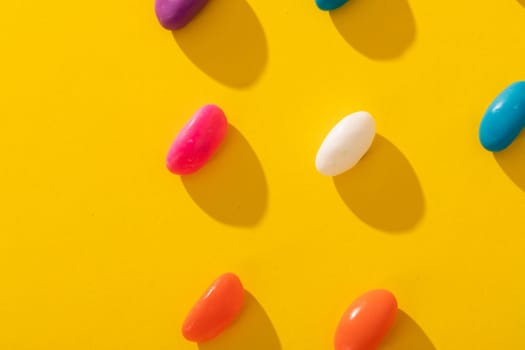 Overhead view of fresh multi colored candies arranged in a row on yellow background. unaltered, sweet food and unhealthy eating concept.
