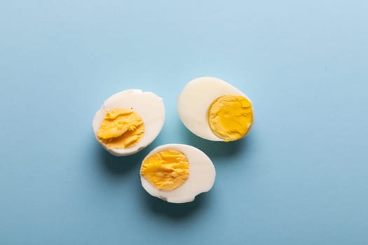 Directly above view of fresh boiled white egg halves on blue background with copy space. unaltered, food, healthy eating and organic concept.