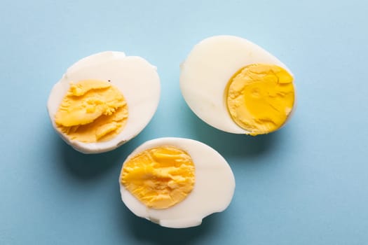 Overhead view of fresh boiled white egg halves on blue background. unaltered, food, healthy eating and organic concept.