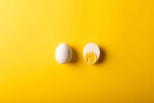 Directly above view of fresh white eggs boiled by copy space against yellow colored background. unaltered, food, healthy eating and organic concept.