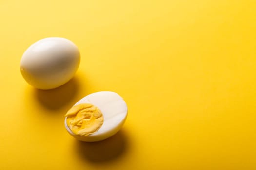 High angle view of freshly boiled white eggs with copy space on yellow background. unaltered, food, healthy eating and organic concept.