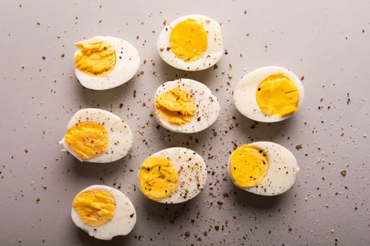 Overhead view of fresh boiled white eggs with peppercorn seasoning on gray background. unaltered, food, healthy eating and organic concept.