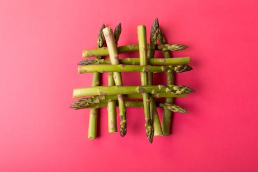 Overhead view of fresh green asparagus stacked on pink background amidst copy space. unaltered, food, healthy eating and organic concept.