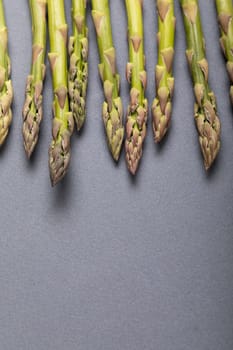 Directly above close-up view of fresh green asparagus over copy space on gray background. unaltered, food, healthy eating and organic concept.