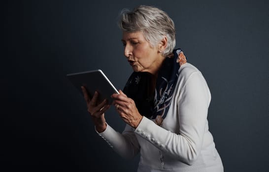 I really would like to own one of these. Studio shot of a cheerful elderly woman standing and giving her tablet a kiss