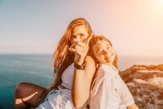 Close up portrait of mom and her teenage daughter hugging and smiling together over sunset sea view. Beautiful woman relaxing with her child.