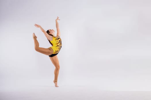 Sportive exercises, standing and stretching the hands. Beautiful muscular woman in indoors studio.