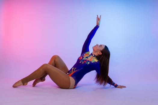 Sportive exercises, standing and stretching the hands. Beautiful muscular woman in indoors studio.