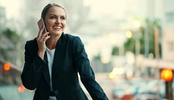 Thats great news. an attractive mature businesswoman using her cellphone while standing on the balcony of her office