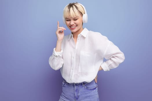 portrait of a modern young pretty blond business woman in a white blouse listening to music during a break. technology business concept.