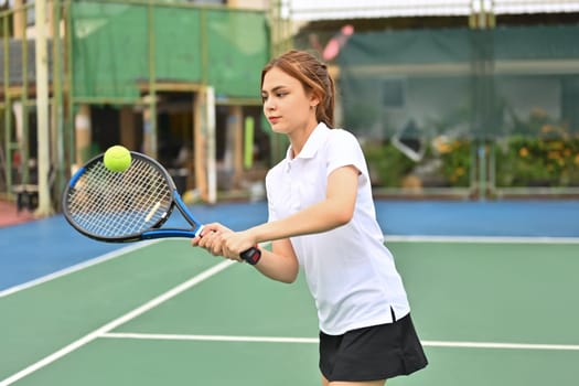 Shot of young sporty woman tennis player hitting ball with a racket during match. Fitness, sport, exercise concept.