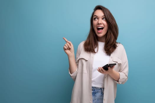 european brunette young woman in a stylish image shows her hand to the side on a blue background with copy space.