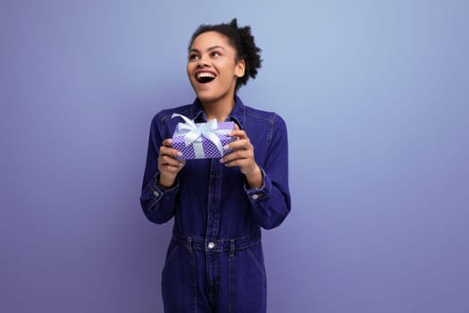young pretty brunette latin woman with afro ponytail dressed in denim clothes received a gift box.