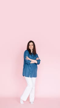 Confident businesswoman in smart casual attire standing with folded hands in front of pink background - Full body shot for professional profile or website banner. Vertical photography