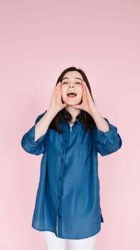 Expressive Joy: Close-Up Portrait of a Cheerful Young Woman's Hands near Open Mouth, Conveying Excitement and Happiness with a Toothy Smile, Isolated on Vibrant Pink Background. Vertical photography.