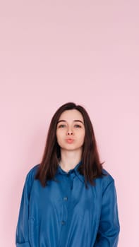 Radiant Elegance: Stunning Portrait of a Gorgeous Lady with Pouted Lips and a Playful Kiss, Wearing a Stylish Smart Casual Shirt, Isolated on a Captivating Pink Background. Vertical photography
