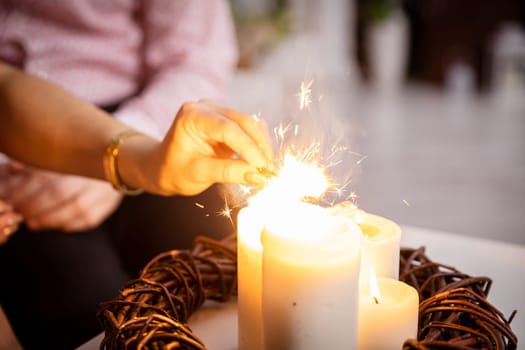 Four lit candles stand on the table as decoration and from them the girl lights fireworks. Romantic mood with burning candles.