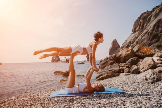 Woman sea yoga. Back view of free calm happy satisfied woman with long hair standing on top rock with yoga position against of sky by the sea. Healthy lifestyle outdoors in nature, fitness concept.