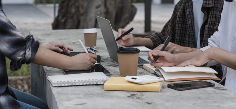 Group of Student working on laptop and record in book together at university. Happy friend successfully completes the thesis report and passed the final exam in asian college...