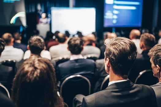 Speaker giving a talk in conference hall at business event. Rear view of unrecognizable people in audience at the conference hall. Business and entrepreneurship concept