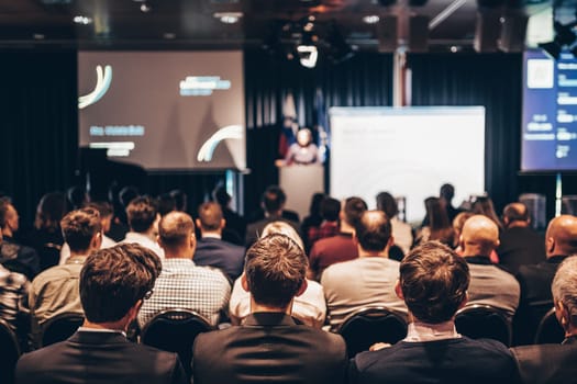 Speaker giving a talk in conference hall at business event. Rear view of unrecognizable people in audience at the conference hall. Business and entrepreneurship concept